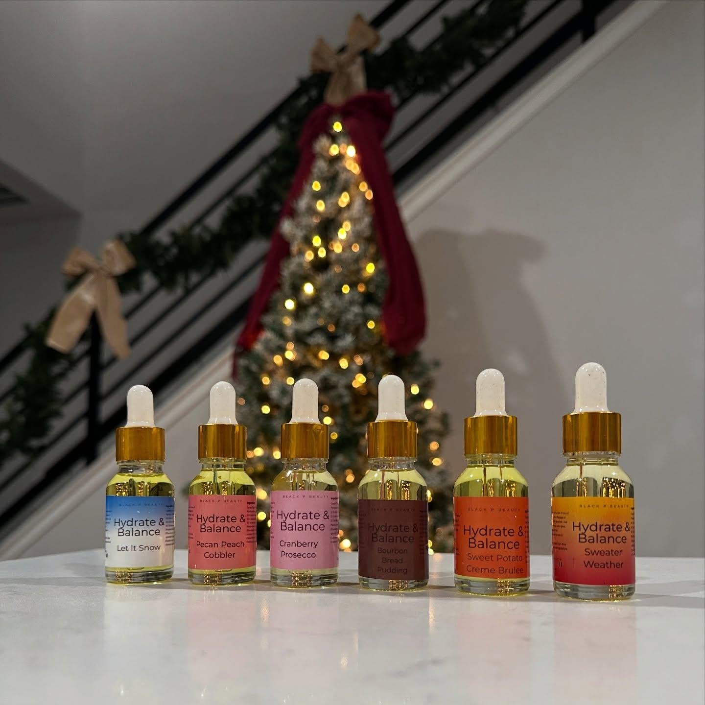 Set of mini body oil product bottles with a Christmas tree in the background