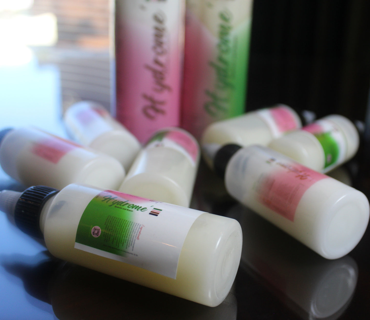 Multiple bottles of Hydome' Shampoo & conditioner, arranged on a reflective surface with a pink bottle in the background.