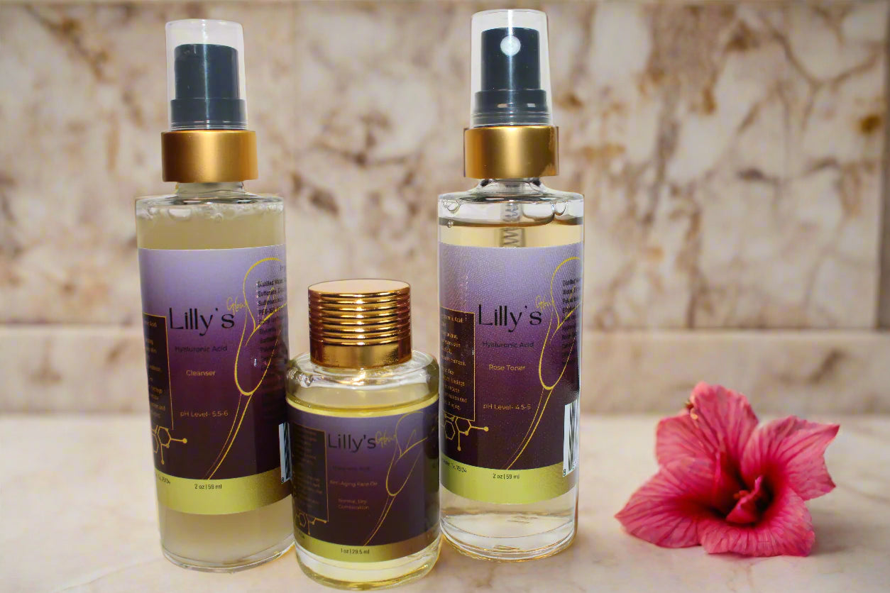  Lilly's Glow Skincare System, featuring a cleanser, toner, and anti-aging face oil with sleek, minimal packaging. The products are surrounded by fresh green leaves, rose petals, and natural ingredients like goji berries and hibiscus flowers, symbolizing the clean, hydrating, and rejuvenating benefits of the skincare system."