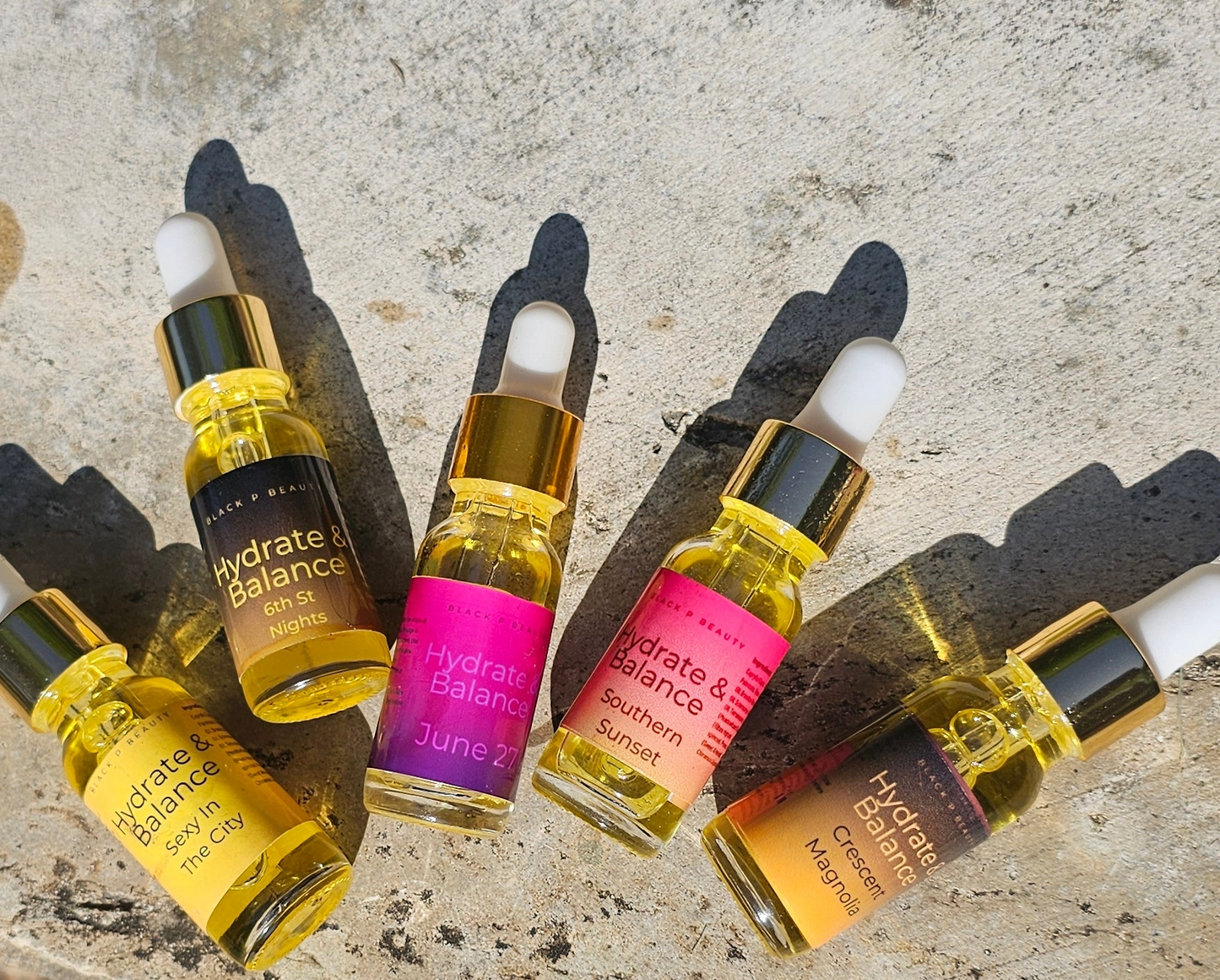 Five small bottles of 'Hydrate & Balance' skincare product on a textured surface